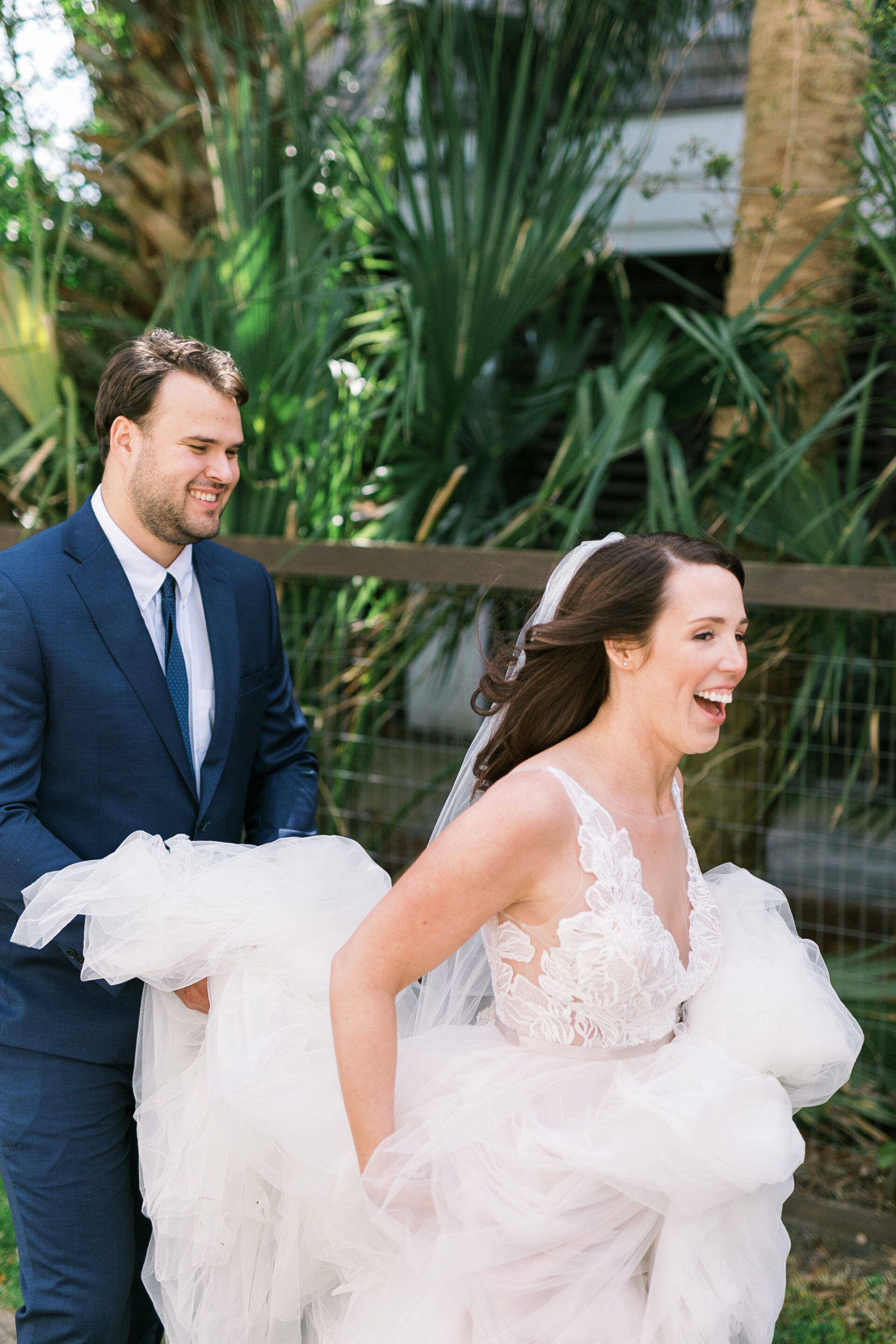 Candid bride and groom share a sweet moment helping the bride with her gorgeous wedding dress