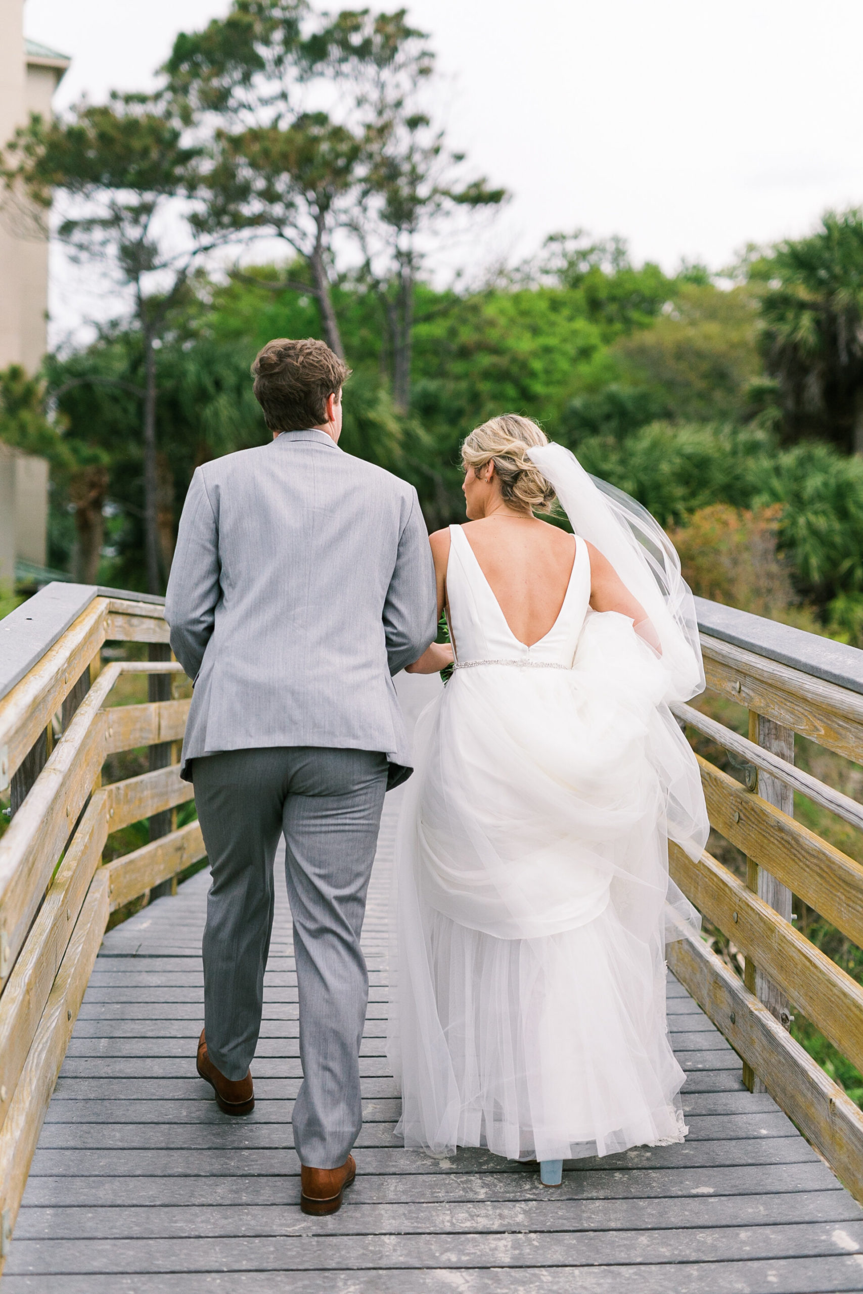 Bride and groom head to the beach for ocean sunset portraits at their beachfront springtime wedding in Charleston.