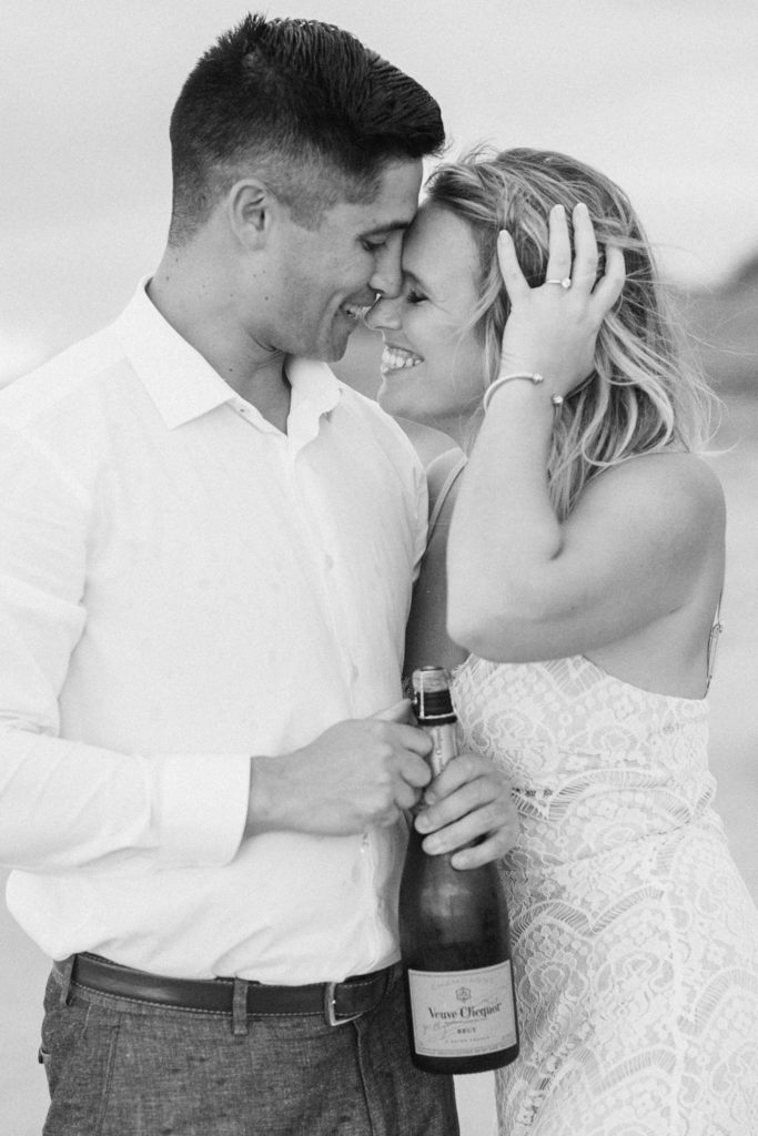 Engaged couple in Charleston, SC on the beach with champagne