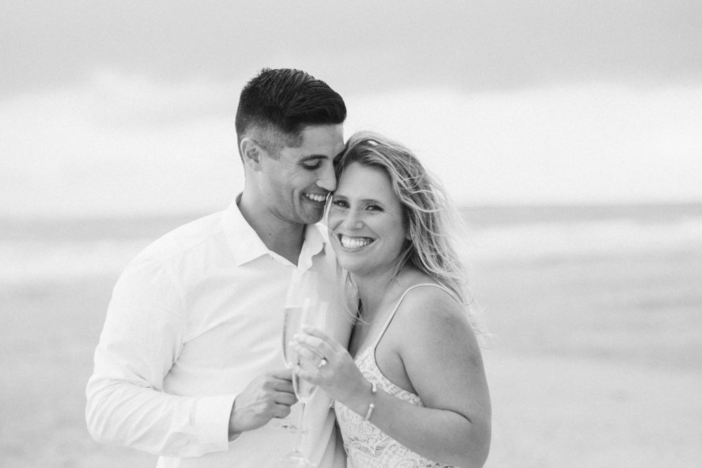 Engaged couple in Charleston, SC on the beach with champagne
