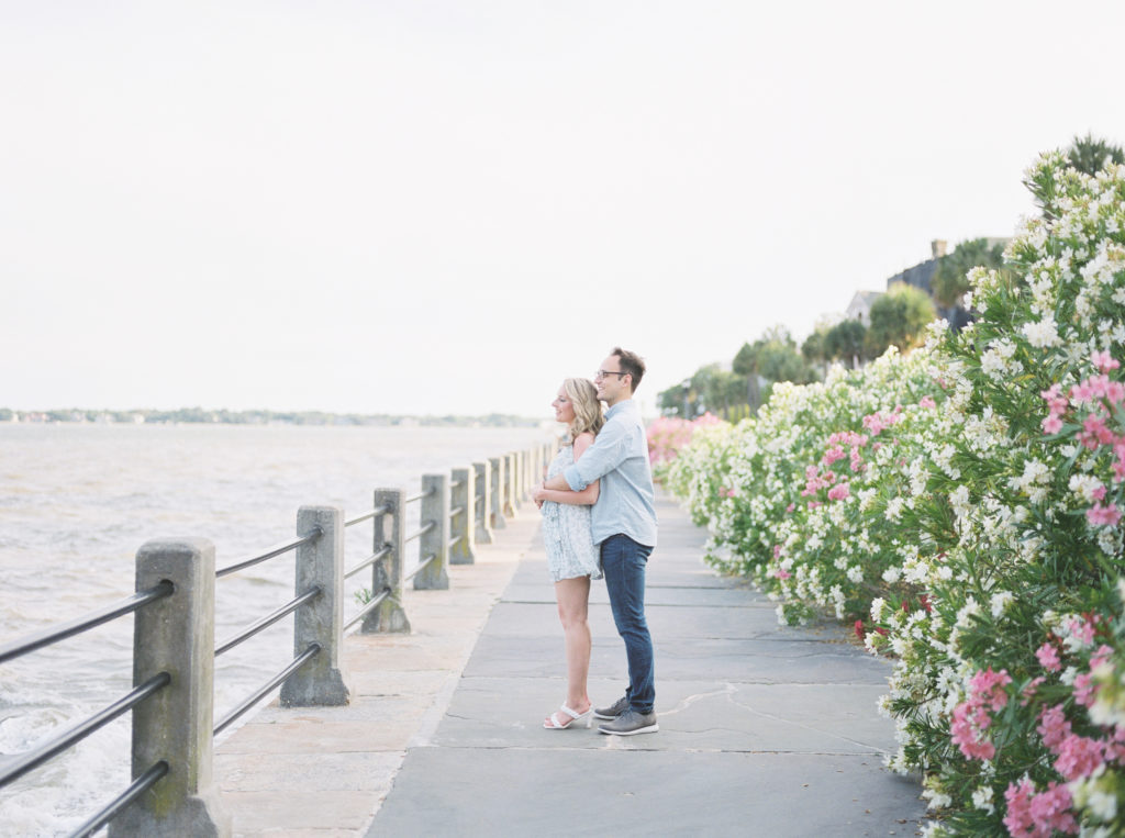 Engaged couple looks out at Charleston Harbour during spring engagement pictures