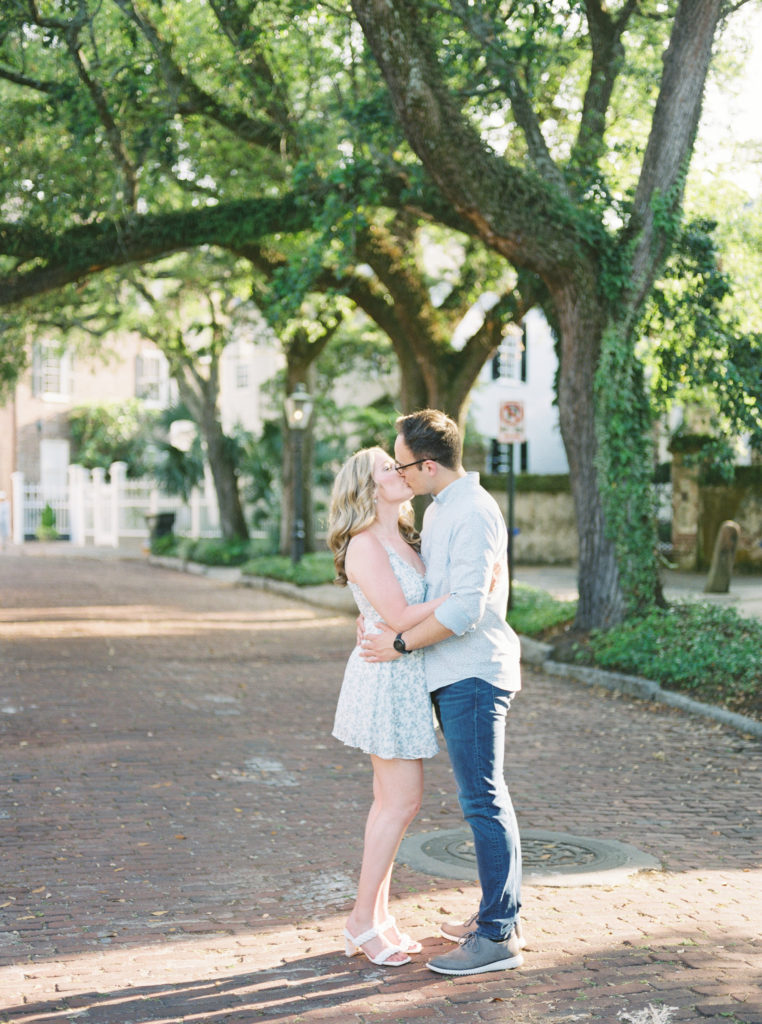 Engaged couple shares a romantic kiss in springtime Charleston engagement portraits