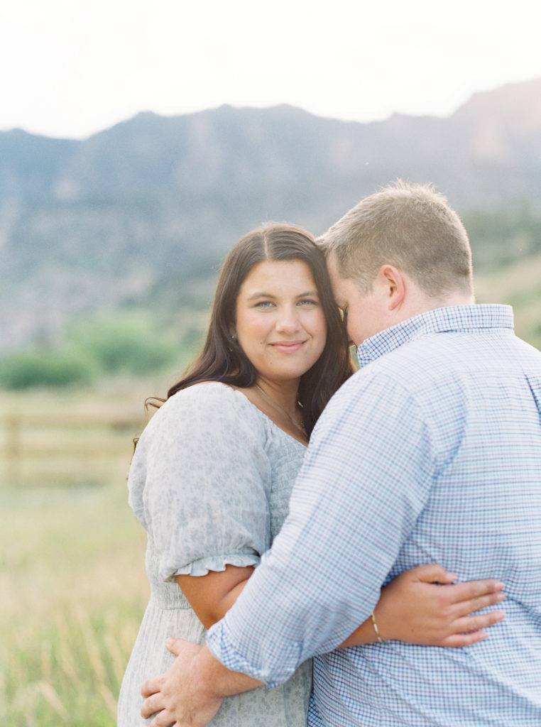Woman smiles at camera with mountains in the background for Boulder engagement photos