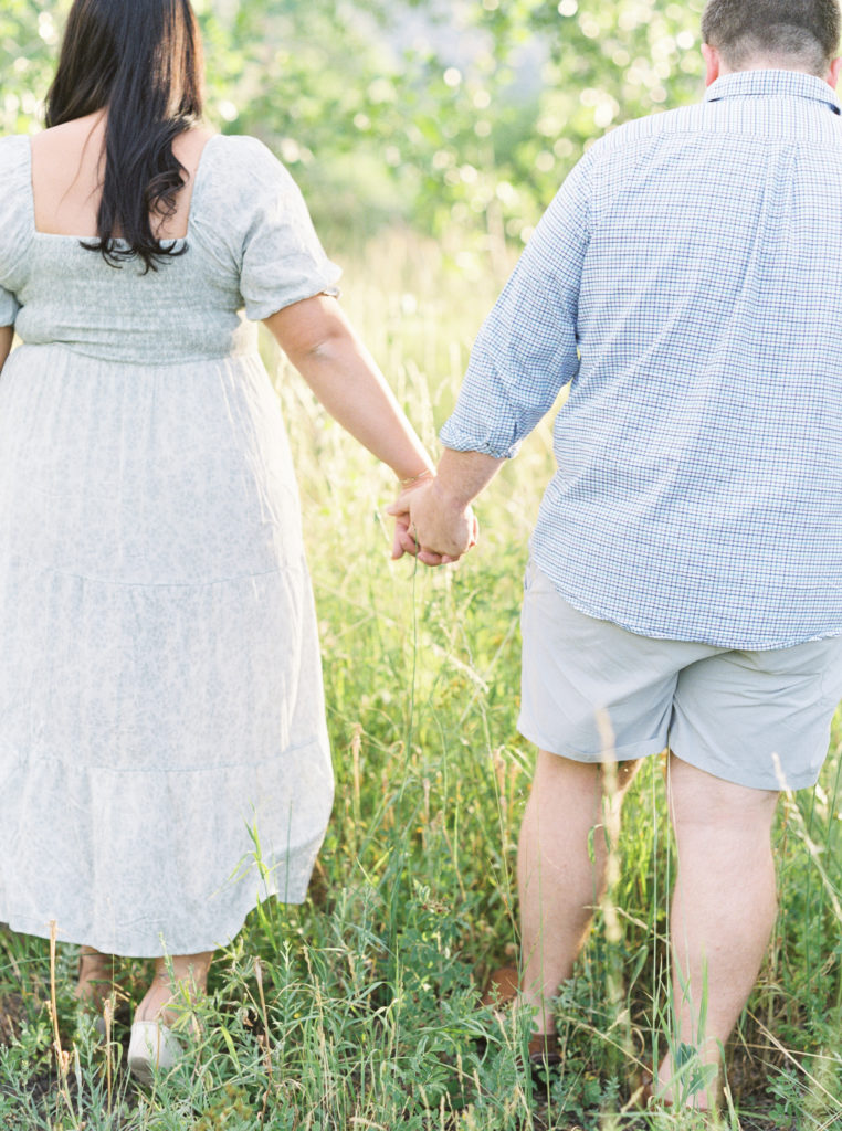 Colorado couple holds hands in a field full of aspen trees for Colorado engagement photos