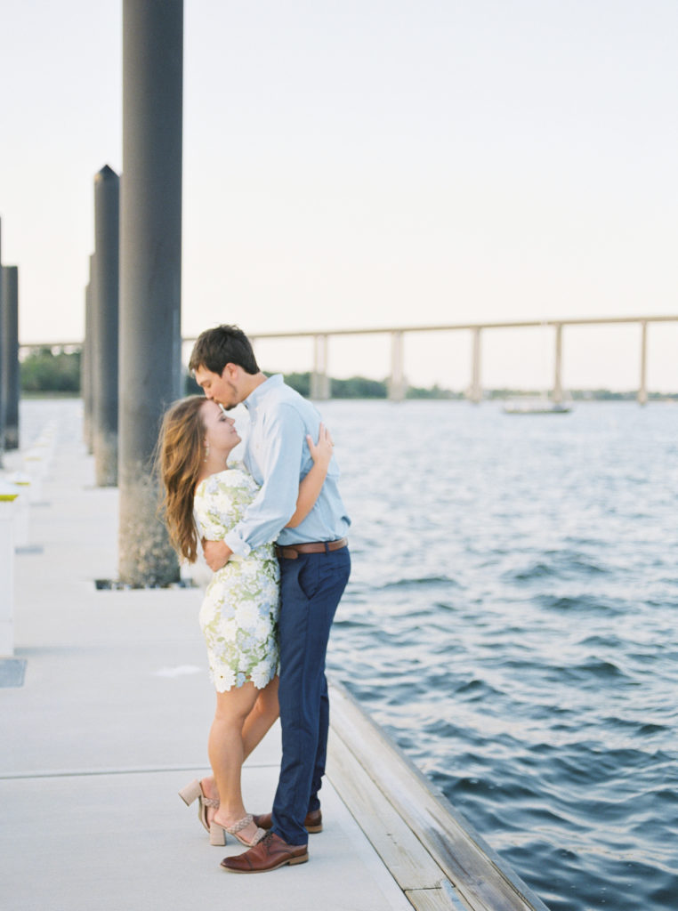 Man kisses woman on forehead in Charleston waterfront engagement photos