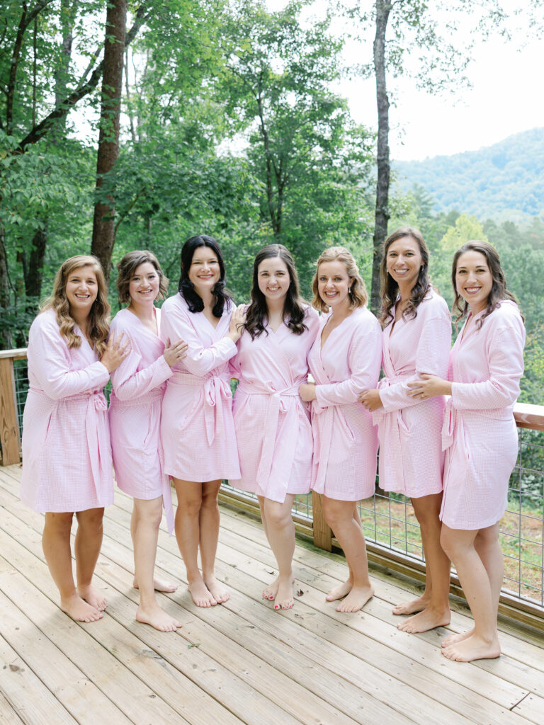 Bridesmaids wear matching pink pajama robes while getting ready