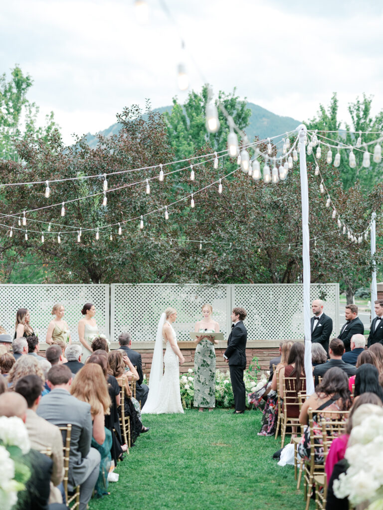 Bride and groom exchange vows in the garden courtyard at St Julien Hotel & Spa with the Flatirons in the background