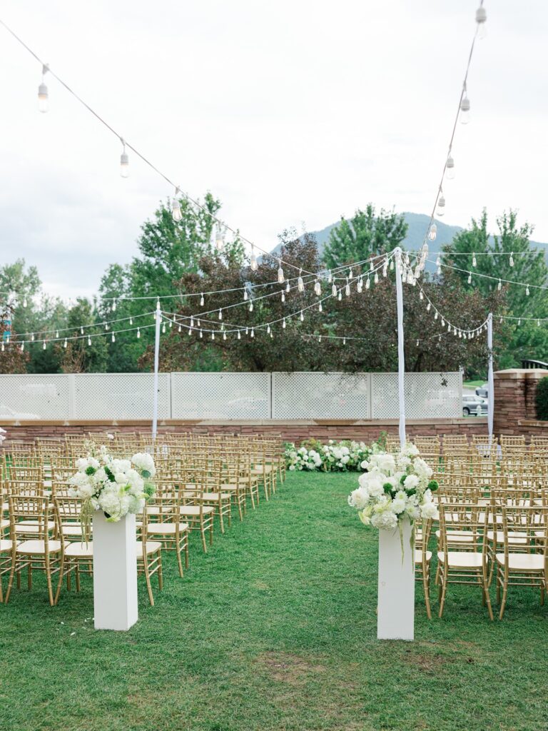 Outdoor wedding ceremony at the St Julien Hotel in Boulder with Flatiron mountain views and lush green and white florals